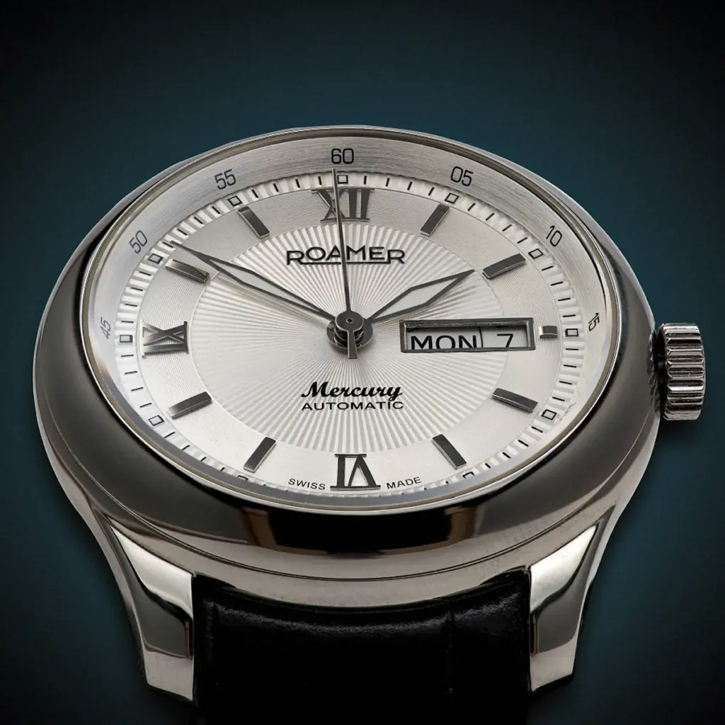 Freigestelltes Produktfoto einer silbernen Armbanduhr mit schwarzem Lederarmband auf dunklem Hintergrund, fotografiert von Ulrich Roth