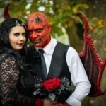 „Paar in Gothic-Hochzeitskostümen – Braut in Schwarz, Bräutigam als Teufel geschminkt“