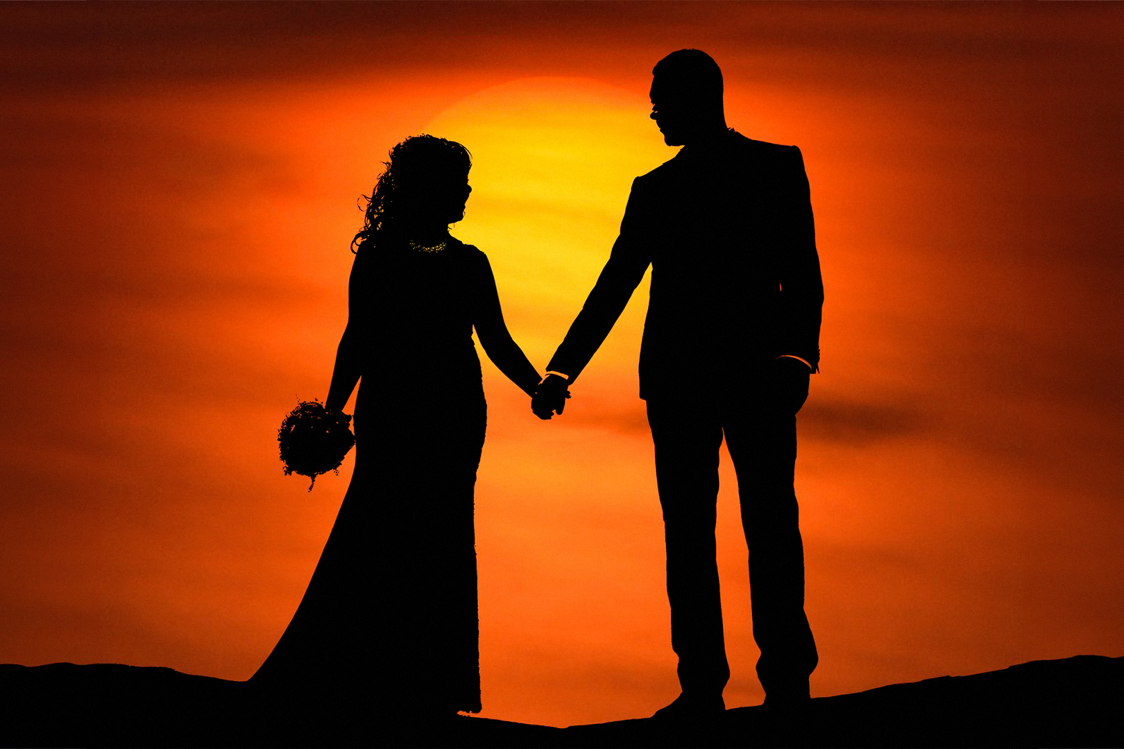Brautpaar bei Sonnenuntergang – romantische Silhouette vor orangefarbenem Himmel