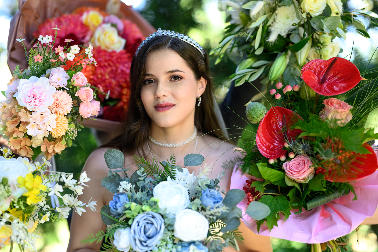 Braut mit Tiara umgeben von farbenfrohen Blumensträußen bei ihrer Sommerhochzeit im Schloss Edesheim am 08.08.2025