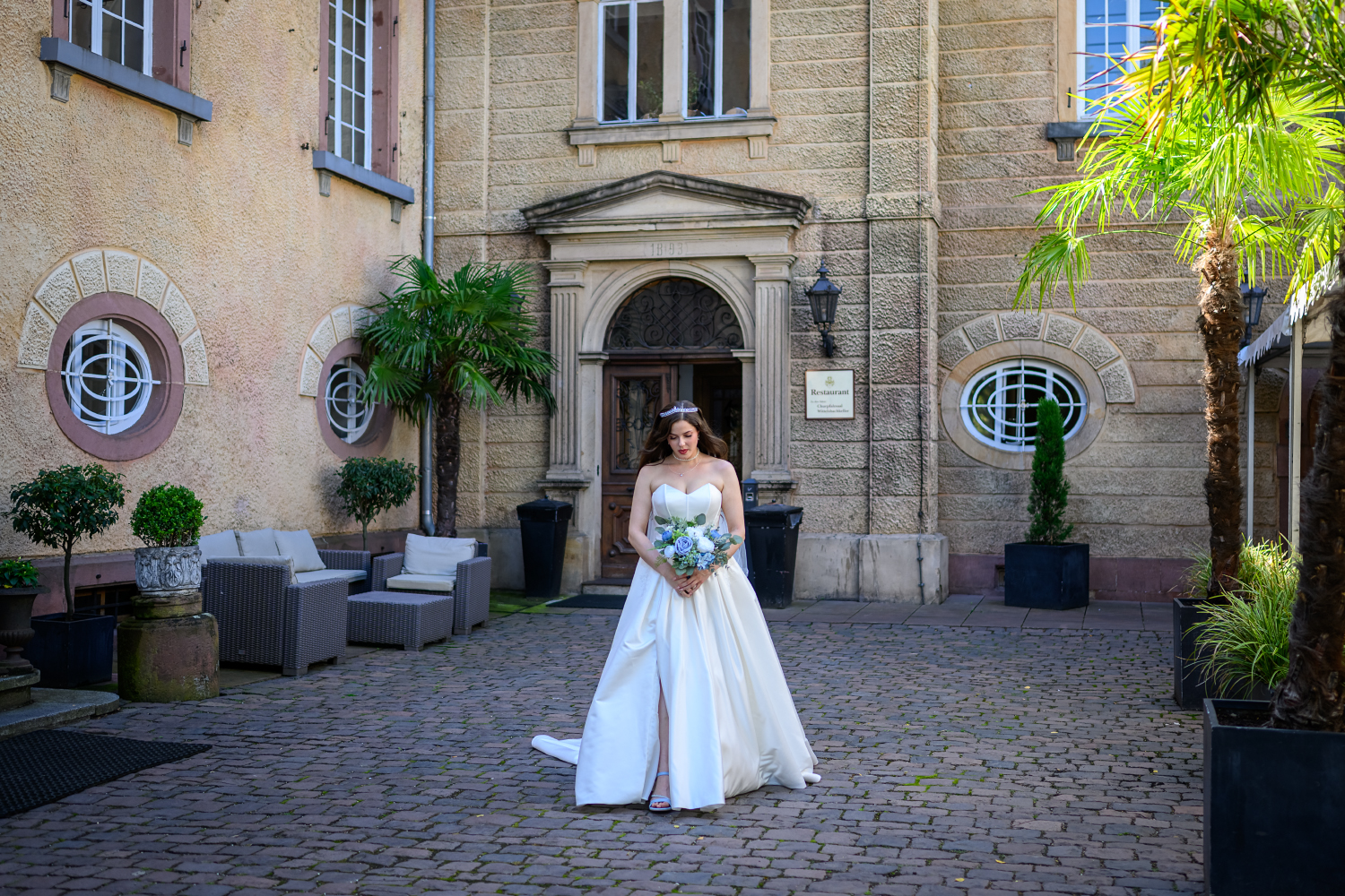 Braut mit Blumenstrauß vor dem Eingang des Schlosses Edesheim bei ihrer Sommerhochzeit am 08.08.2025