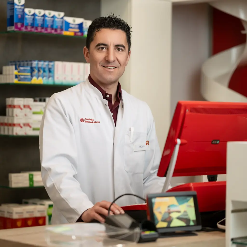 Apotheker im weißen Kittel steht hinter dem Tresen in einer modernen Apotheke, fotografiert von Ulrich Roth