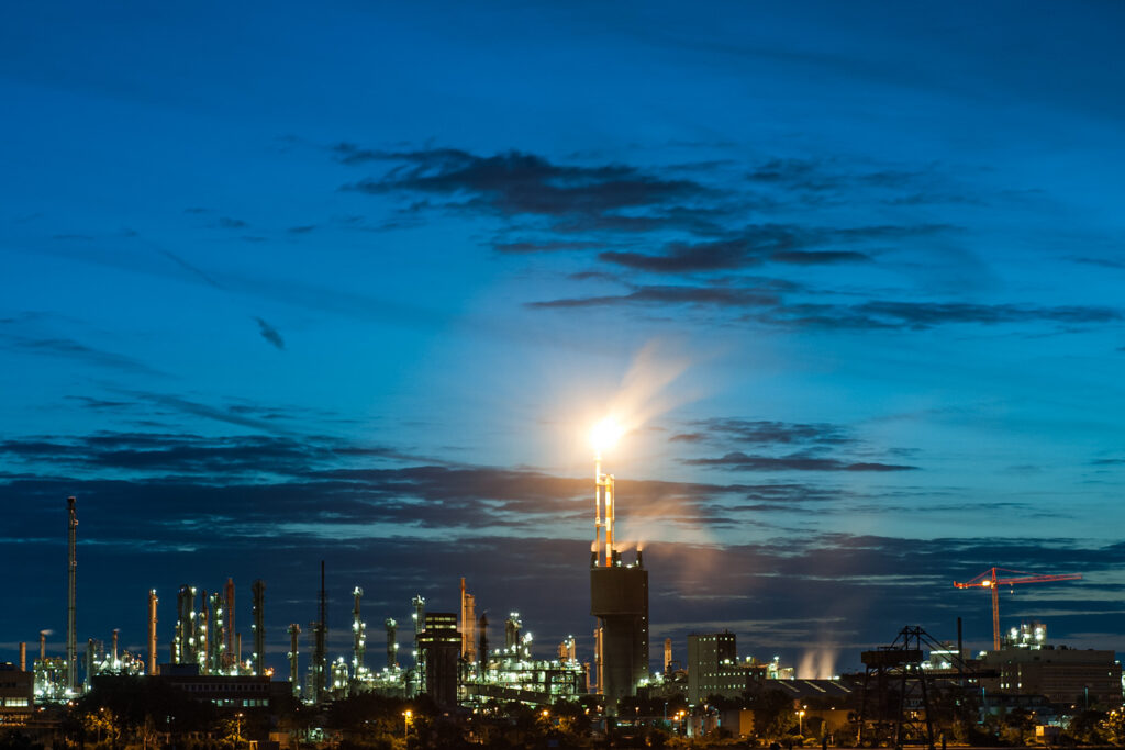 Beleuchtetes Chemiewerk in Ludwigshafen mit Fackelanlage während der Blauen Stunde.