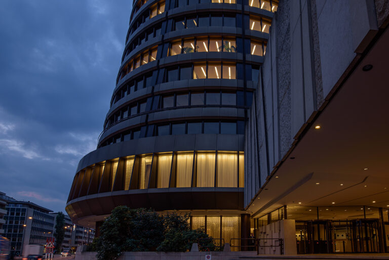 Modernes Bürogebäude mit beleuchteten Büros in Basel während der blauen Stunde
