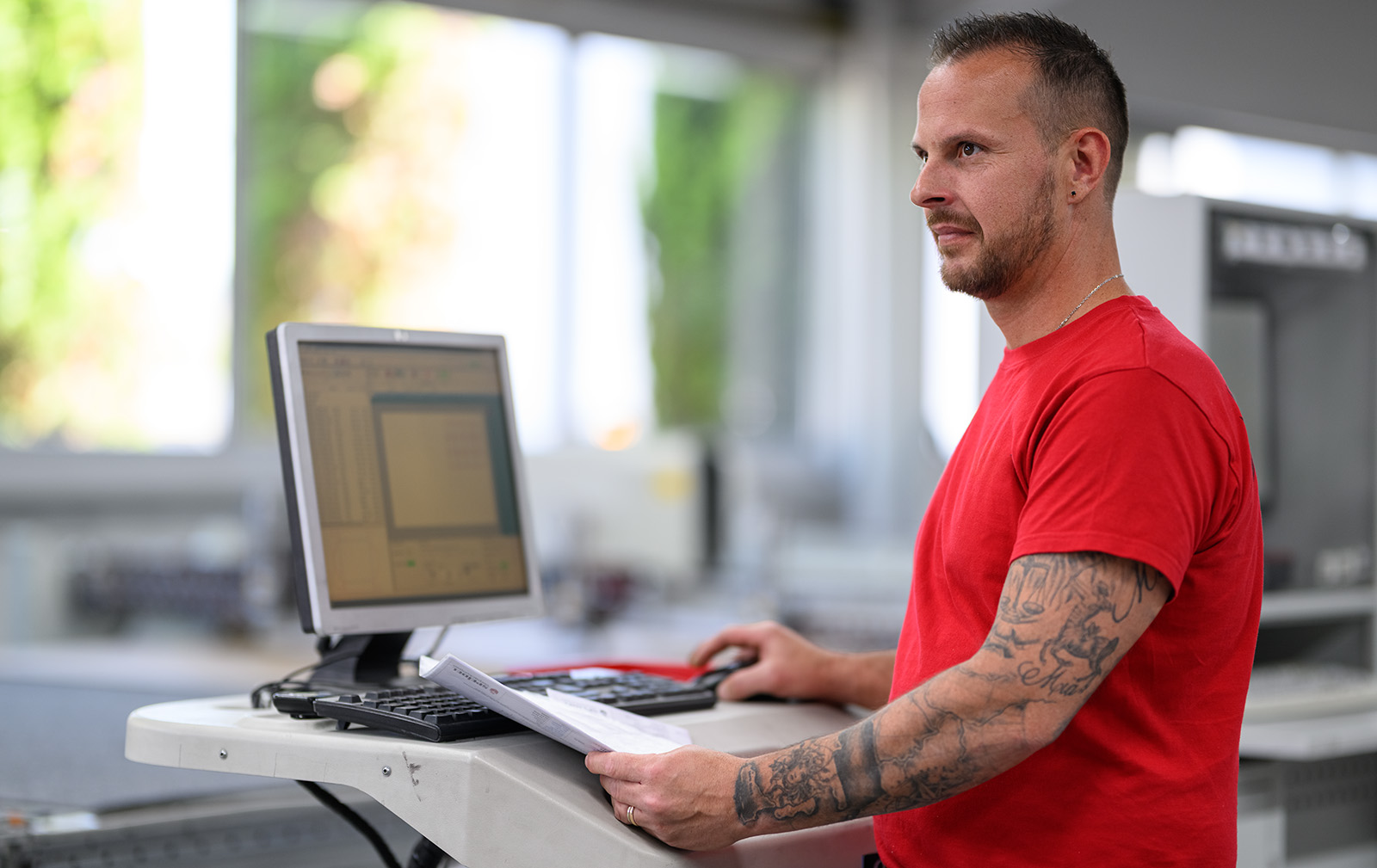 Maschinenbediener überwacht eine CNC-Anlage an einem Computerarbeitsplatz in der Produktion.