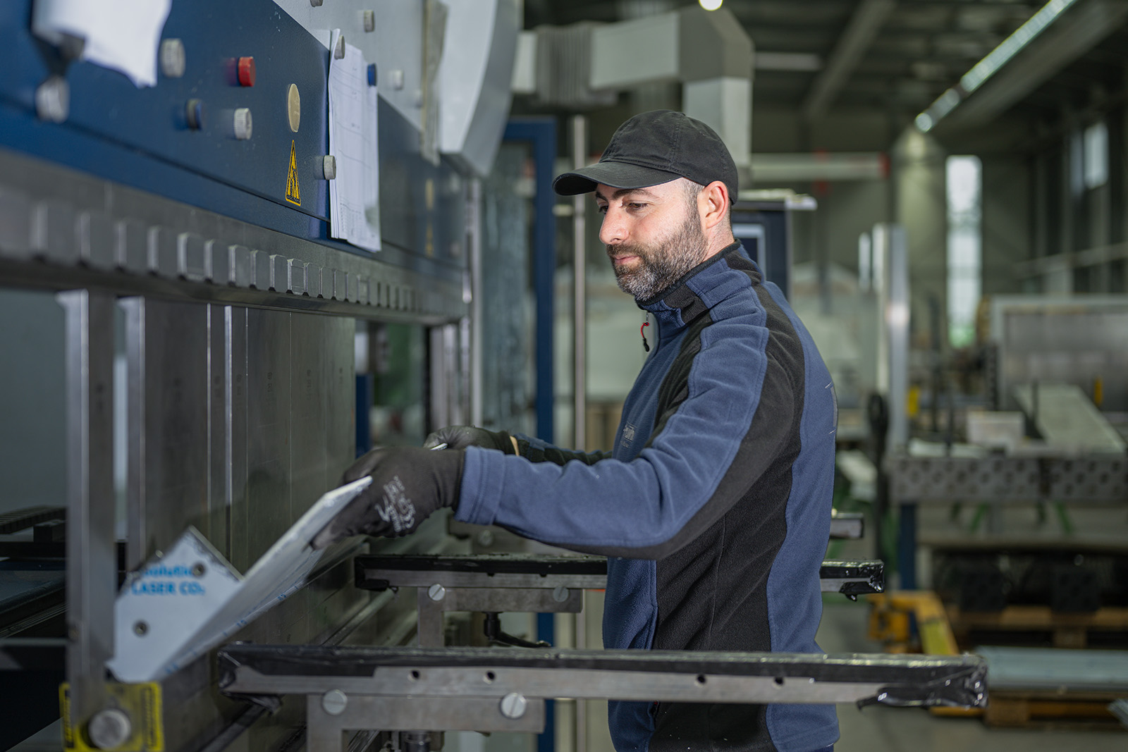 Mitarbeiter bedient eine CNC-Abkantpresse in einer modernen Metallverarbeitung.