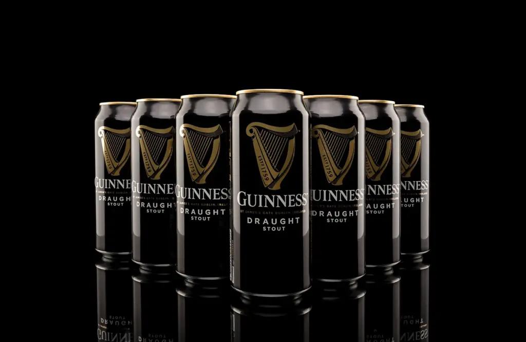 Schwarze Guinness-Getränkedosen auf spiegelnder Fläche vor schwarzem Hintergrund