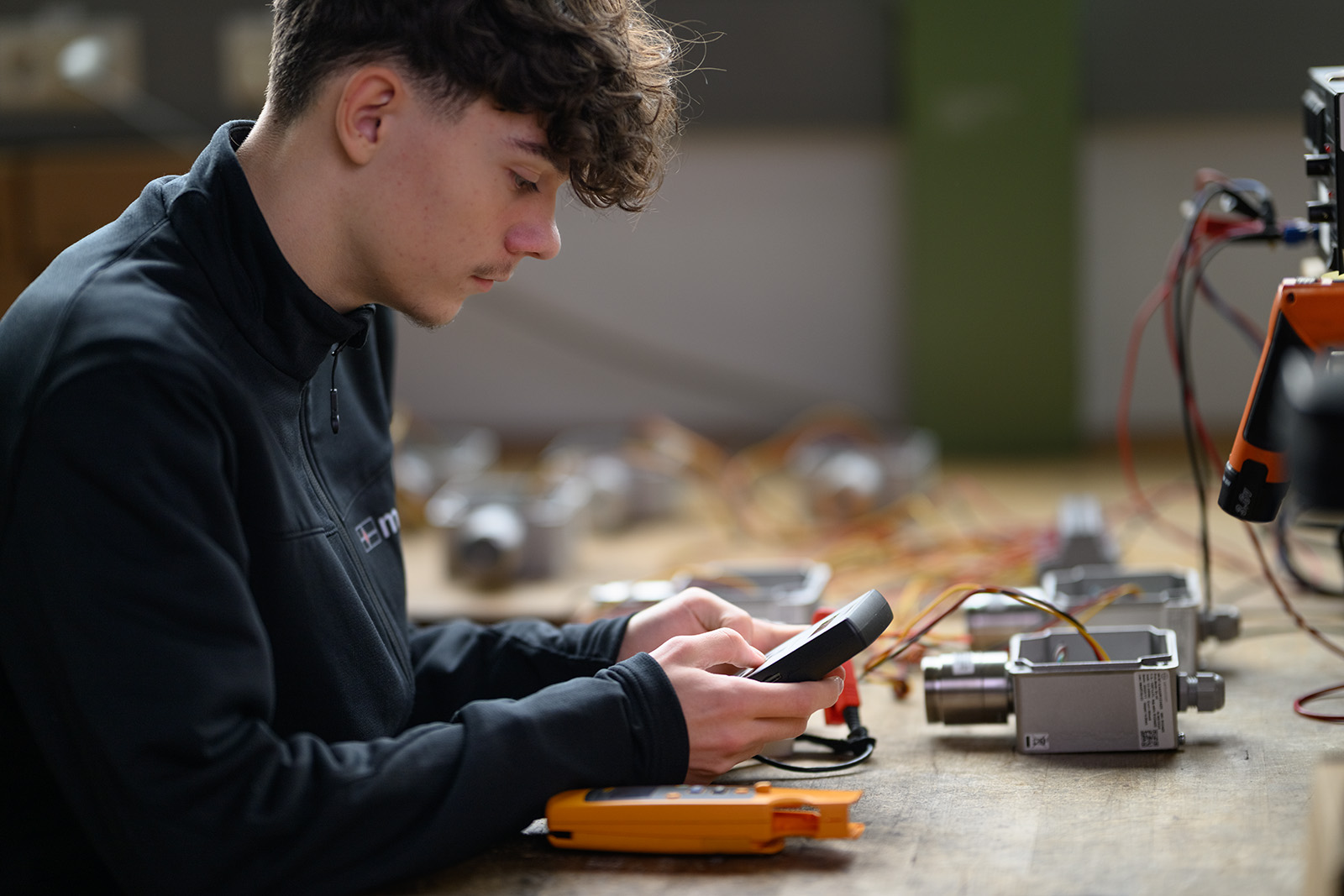 Mitarbeiter prüft industrielle Bauteile mit einem elektronischen Messgerät.