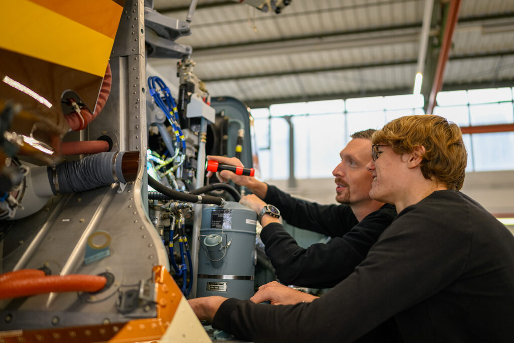 Techniker erklärt einem Auszubildenden die Wartung einer Industrieanlage.