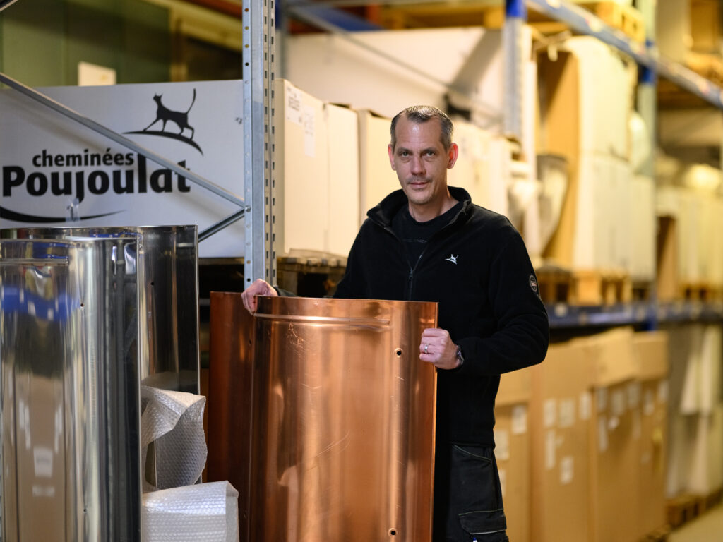 Mitarbeiter eines Kaminsystem-Herstellers präsentiert ein Bauteil in der Lagerhalle.