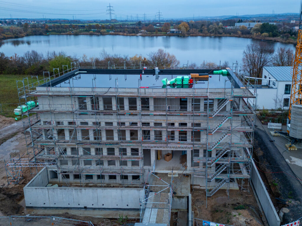 Baustellenfotografie: Rohbau mit Gerüst und Baukran, Luftaufnahme zur blauen Stunde