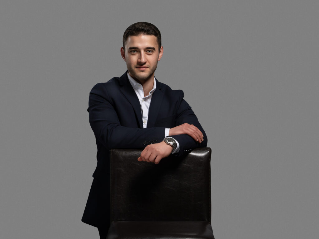 Businessportrait eines Geschäftsmanns im dunklen Anzug vor grauem Hintergrund