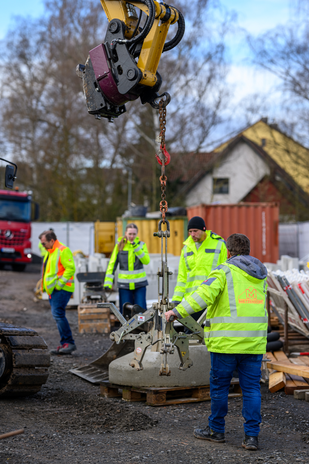 Zwei Mitarbeiter führen ein Betonfertigteil beim Kraneinheben