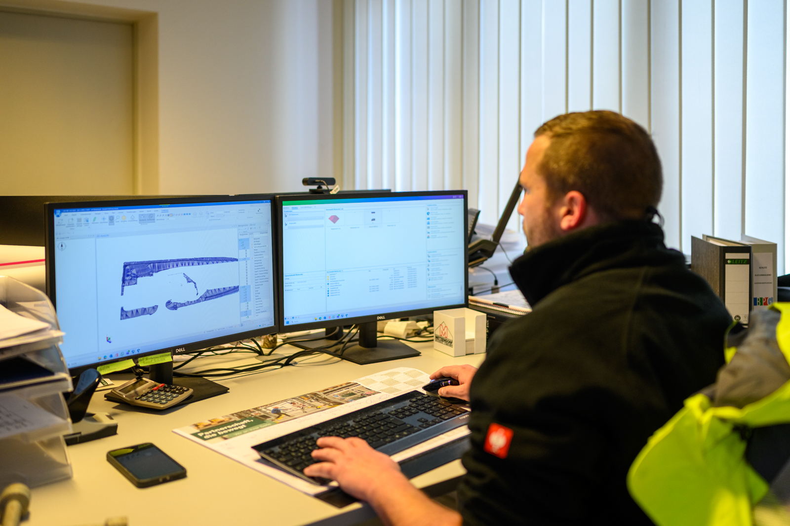 Mitarbeiter an einem Doppelmonitor-Arbeitsplatz in der Bauplanung