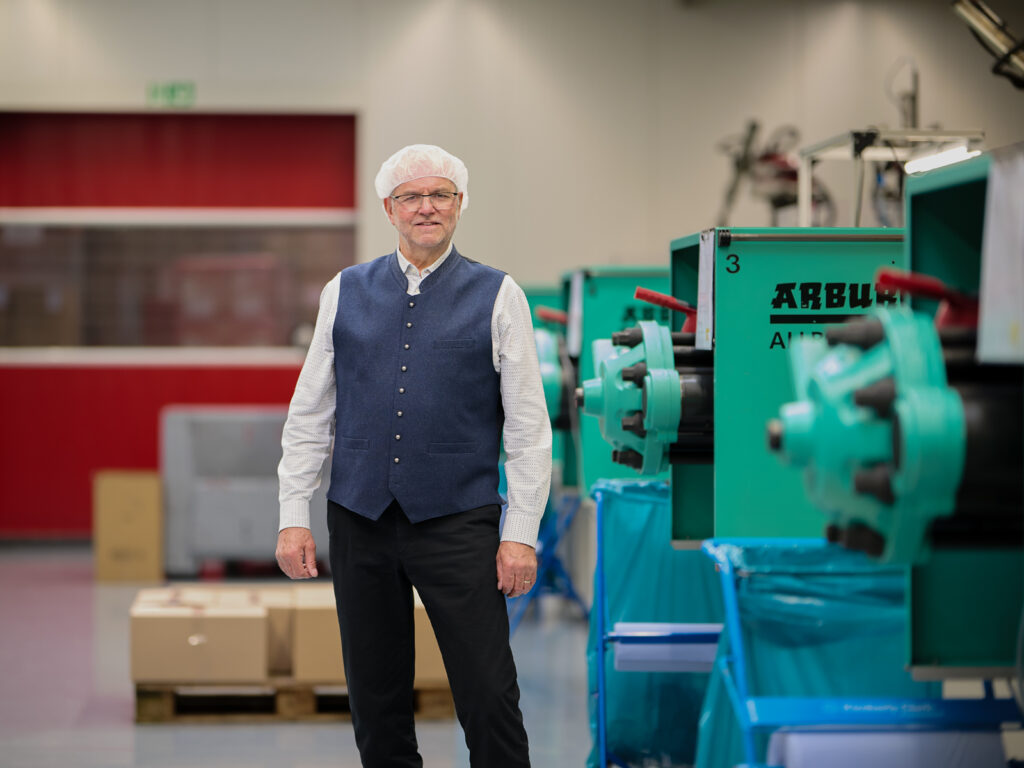 Geschäftsführer der Firma Terraplastik steht vor laufenden Arburg-Spritzgussmaschinen in der Produktionshalle.