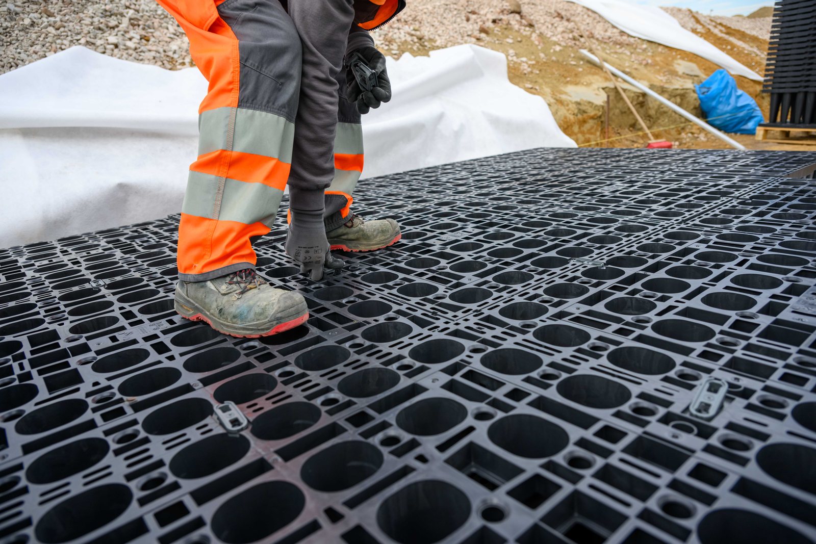 Hände in Arbeitshandschuhen setzen ein GRAF EcoBloc Modul auf die untere Lage
