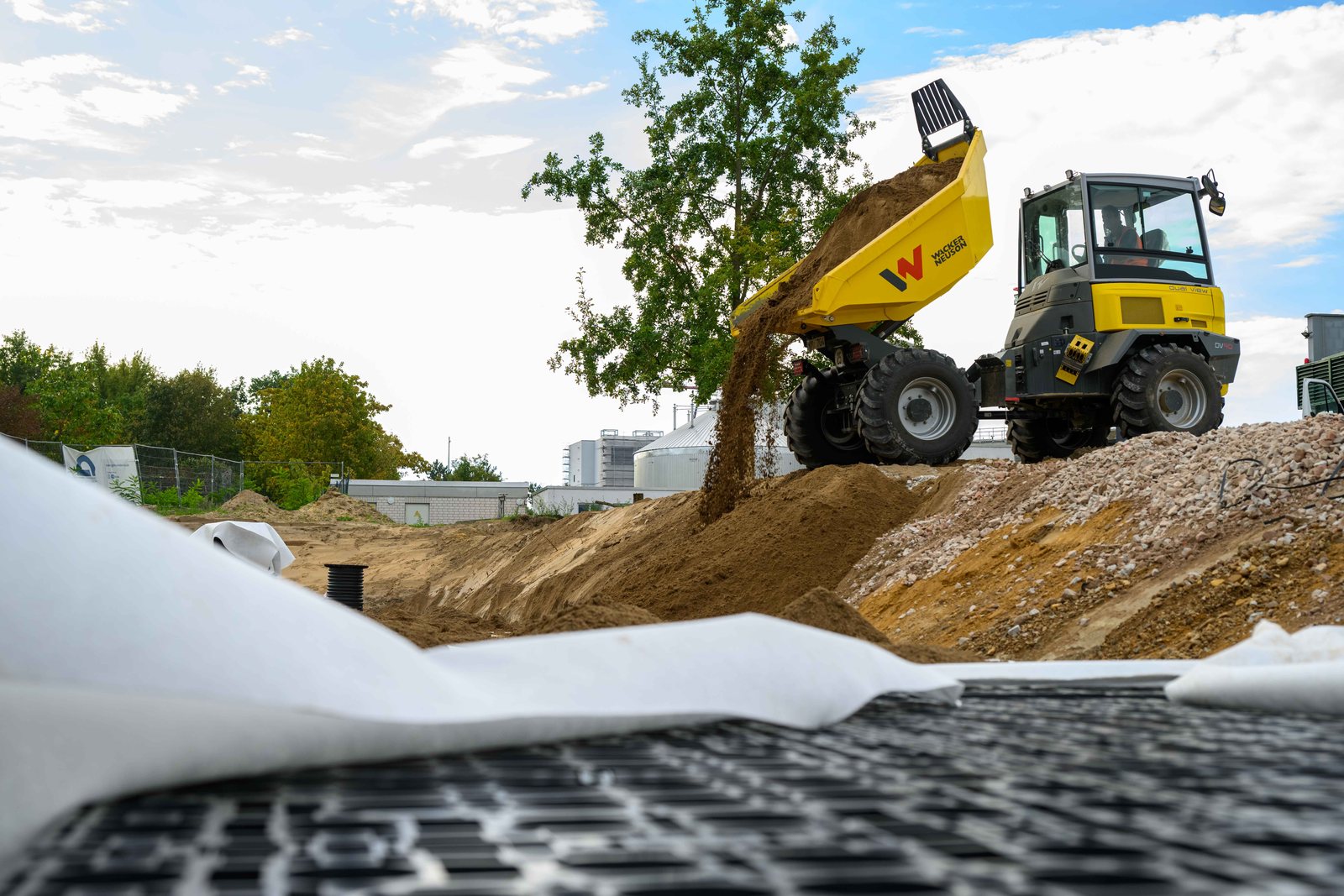 Ein Dumper kippt Sand neben die mit Vlies abgedeckte EcoBloc-Rigole