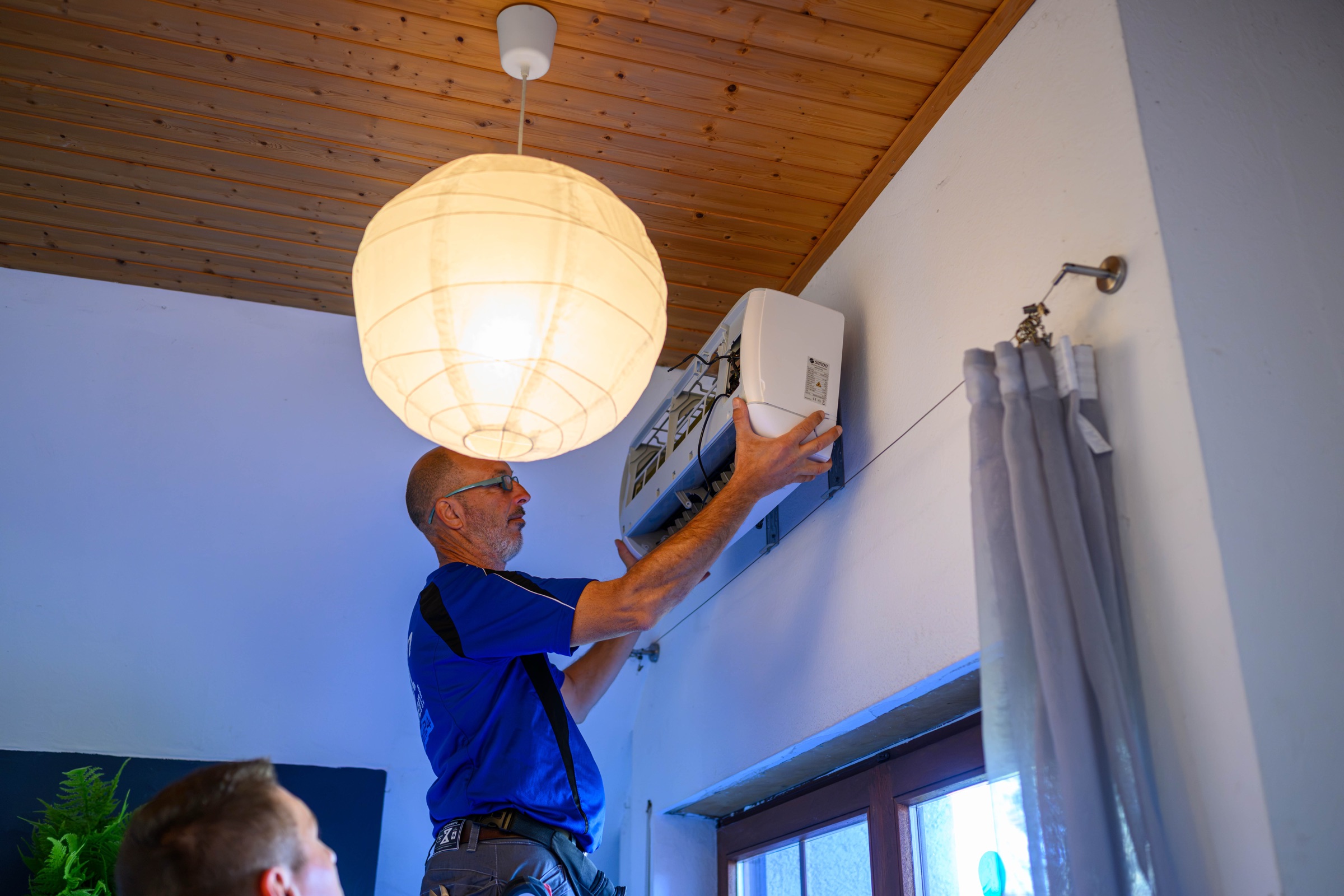 Techniker setzt ein Klimagerät an der Wand ein – Unternehmensfotografie in Karlsruhe